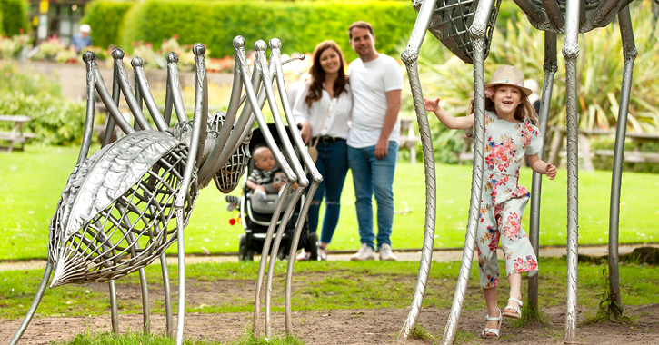 family smiling as little girl runs through gardens at Durham University Botanic Garden